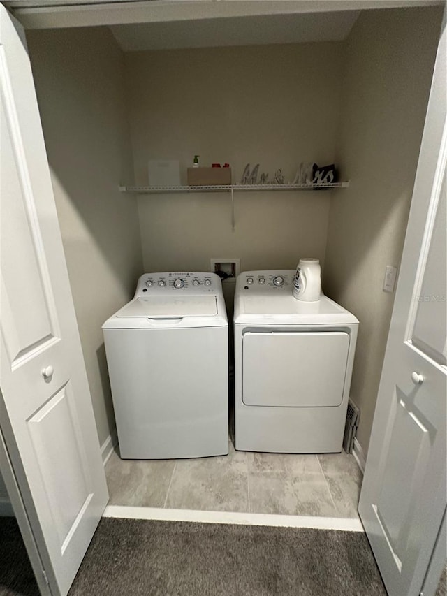 clothes washing area with light colored carpet and washer and clothes dryer