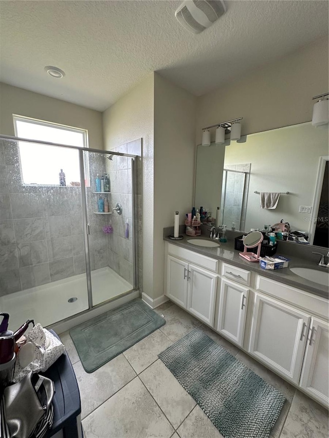 bathroom featuring vanity, a textured ceiling, tile patterned floors, and a shower with shower door