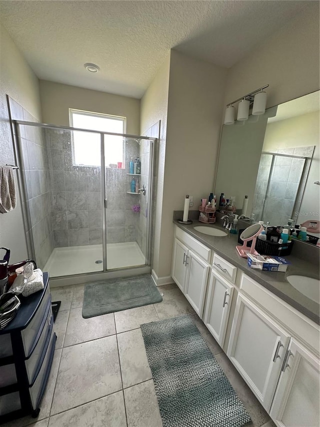 bathroom with vanity, a textured ceiling, tile patterned floors, and a shower with door