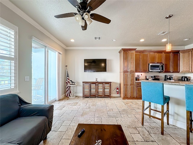 kitchen with ornamental molding, appliances with stainless steel finishes, decorative light fixtures, a kitchen breakfast bar, and ceiling fan