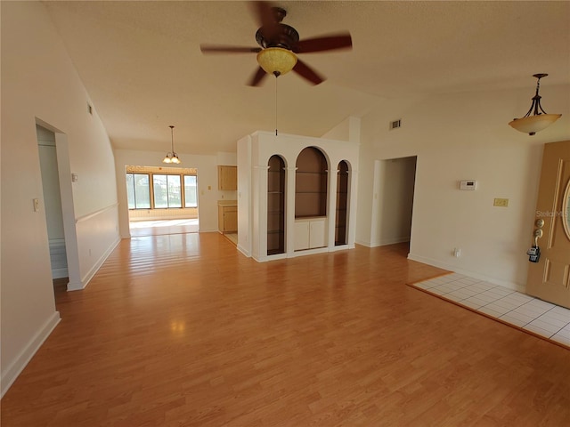 unfurnished living room featuring lofted ceiling, ceiling fan with notable chandelier, and light hardwood / wood-style flooring