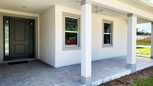 entrance to property featuring covered porch and ceiling fan