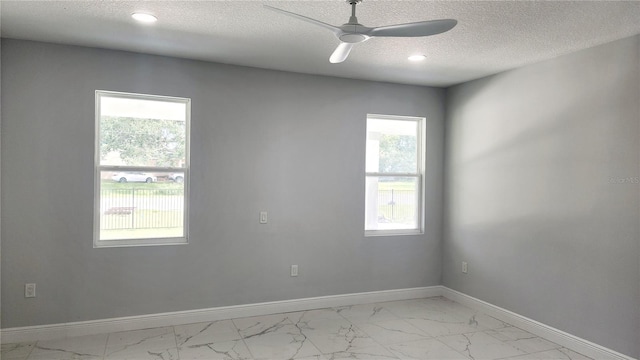 spare room featuring ceiling fan, a healthy amount of sunlight, and a textured ceiling