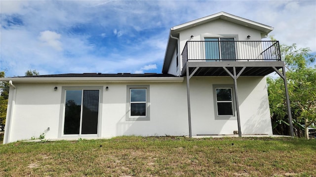 back of property with a lawn and a balcony