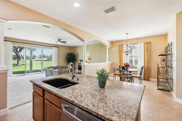 kitchen with pendant lighting, an island with sink, decorative columns, and sink