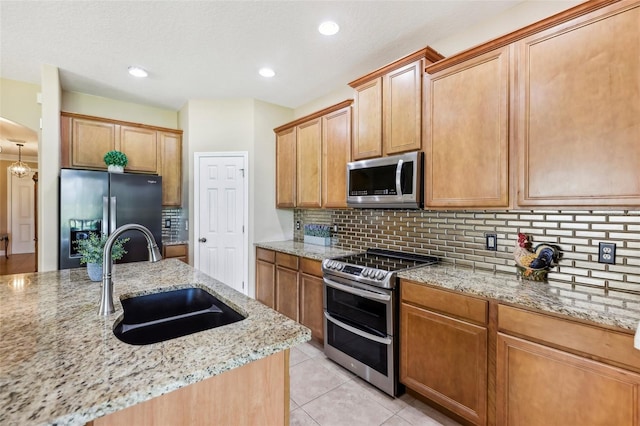 kitchen featuring light stone countertops, sink, stainless steel appliances, decorative backsplash, and light tile patterned floors