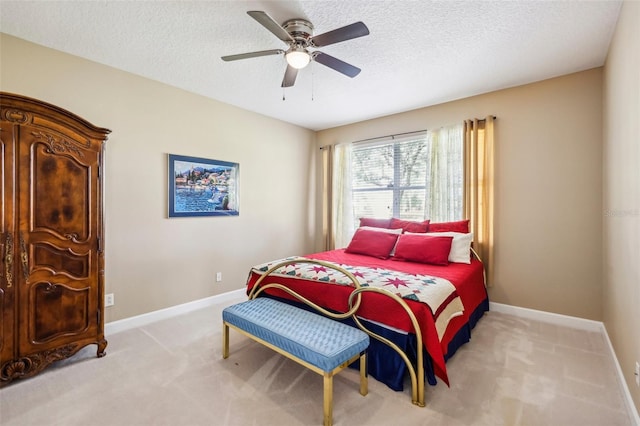 bedroom with ceiling fan, light colored carpet, and a textured ceiling