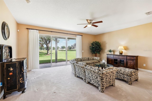 carpeted living room featuring ceiling fan and a textured ceiling