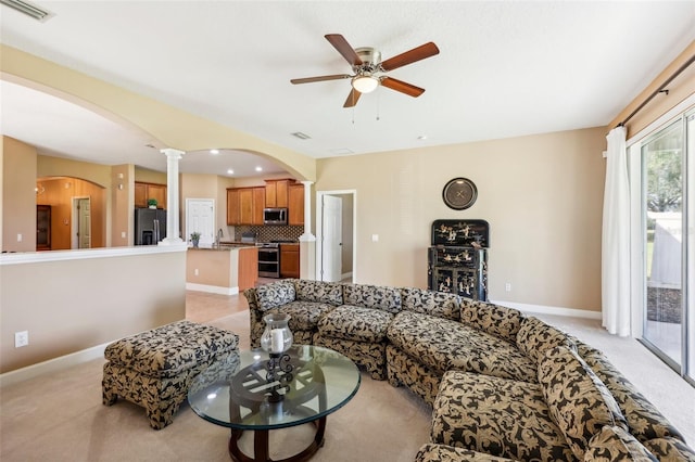 living room with light carpet, decorative columns, and ceiling fan