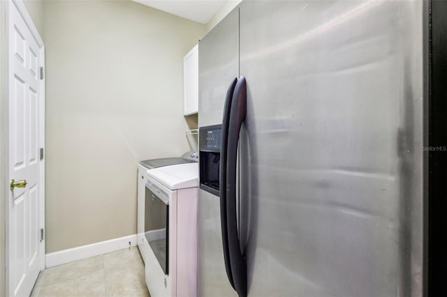 laundry area featuring cabinets, separate washer and dryer, and light tile patterned floors