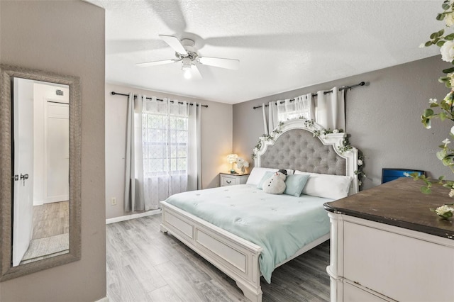 bedroom with light hardwood / wood-style floors, ceiling fan, and a textured ceiling