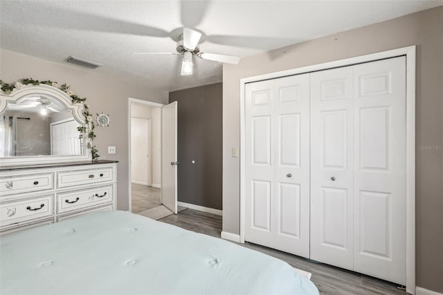 unfurnished bedroom with a closet, light wood-type flooring, a textured ceiling, and ceiling fan