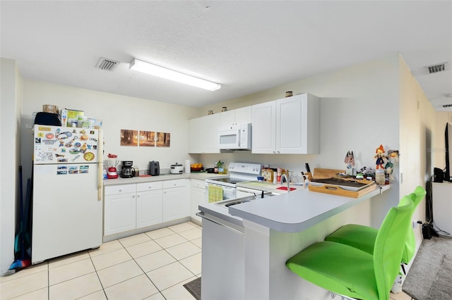 kitchen with white cabinetry, kitchen peninsula, light tile patterned flooring, and white appliances