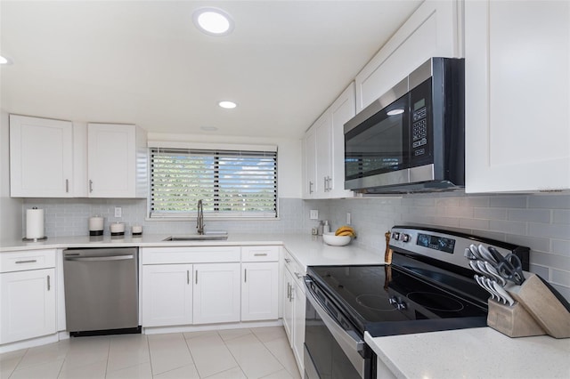 kitchen featuring sink, light tile patterned floors, tasteful backsplash, white cabinets, and appliances with stainless steel finishes