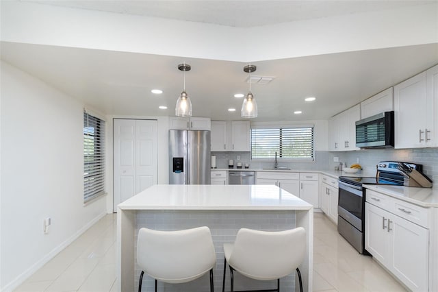 kitchen with white cabinetry, stainless steel appliances, pendant lighting, a breakfast bar, and a kitchen island