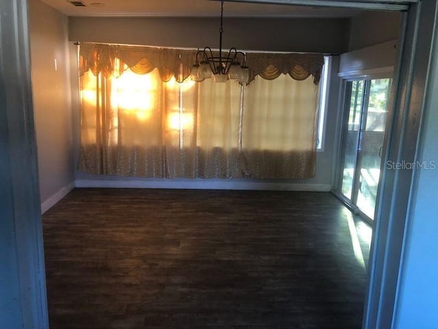 unfurnished dining area with dark hardwood / wood-style floors and an inviting chandelier