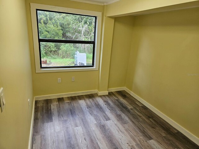 empty room with hardwood / wood-style flooring and crown molding