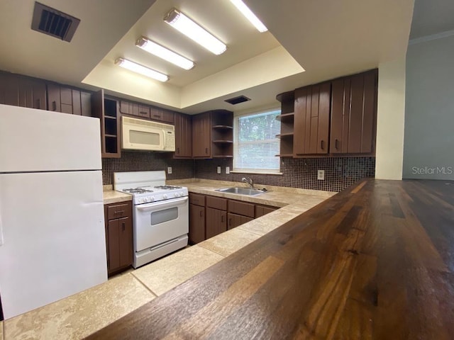 kitchen with dark brown cabinetry, white appliances, sink, and tasteful backsplash