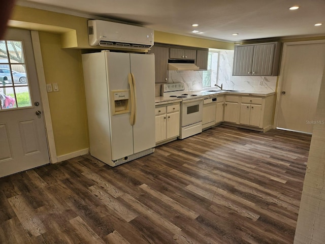 kitchen with sink, tasteful backsplash, dark hardwood / wood-style floors, an AC wall unit, and white appliances