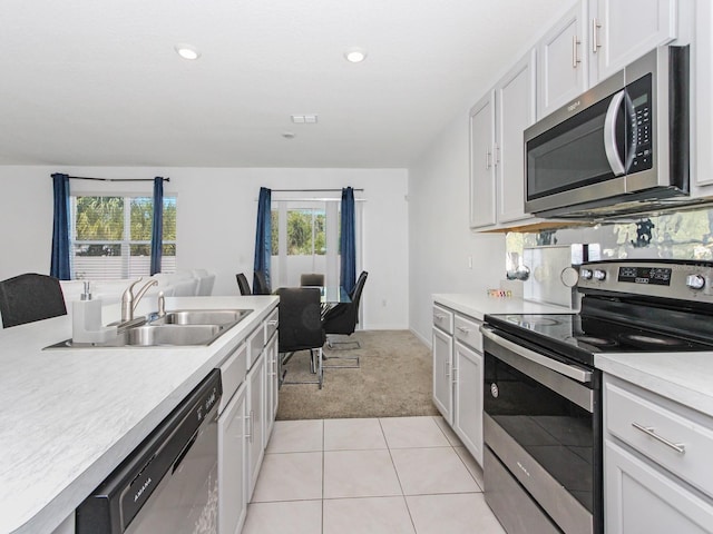 kitchen featuring sink, light colored carpet, white cabinets, and appliances with stainless steel finishes