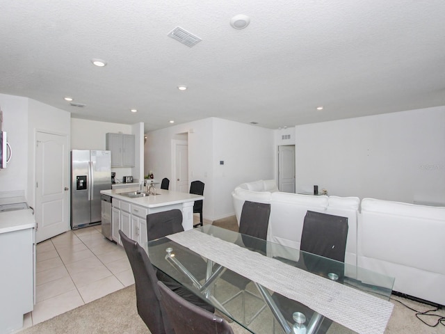 dining space with sink, washer / clothes dryer, a textured ceiling, and light tile patterned flooring