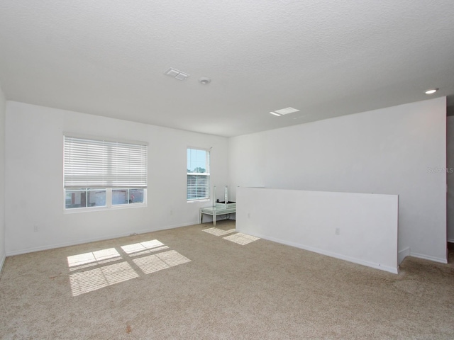 empty room with light carpet and a textured ceiling