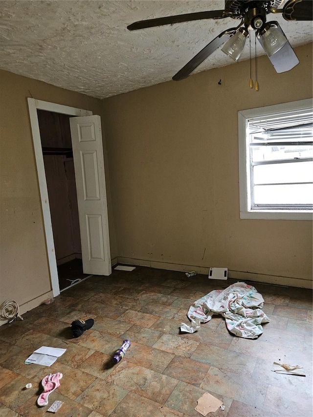 unfurnished bedroom featuring a ceiling fan, a closet, and a textured ceiling