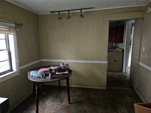 dining area featuring a textured ceiling, ornamental molding, and wooden walls