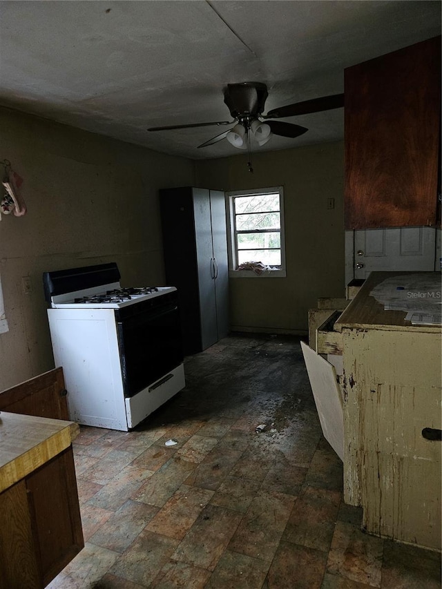 kitchen with light countertops, ceiling fan, and gas range gas stove