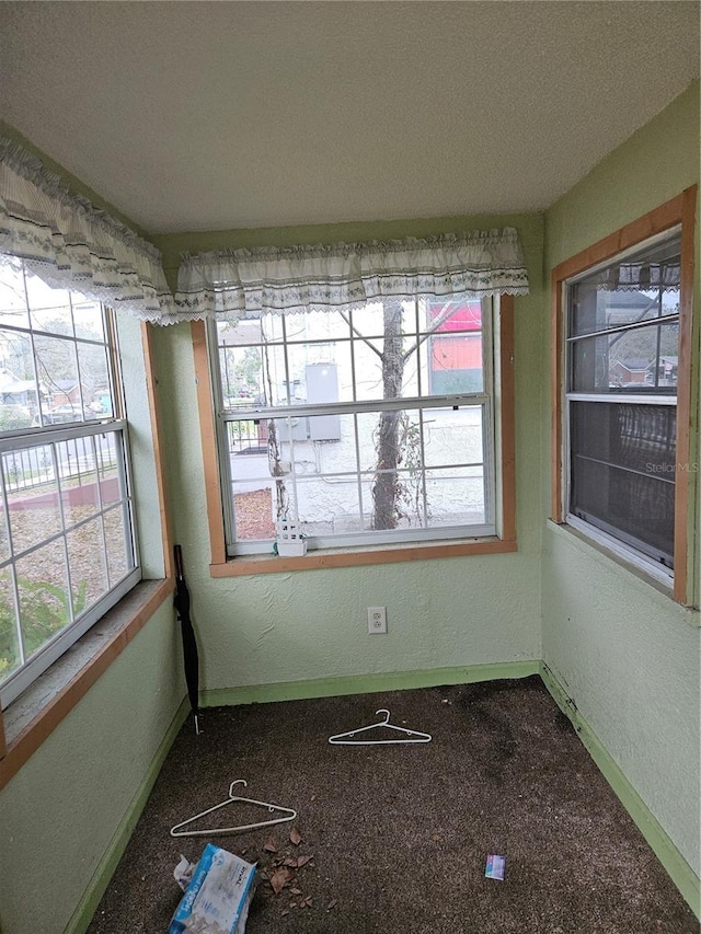 interior space with a healthy amount of sunlight, a textured wall, and baseboards