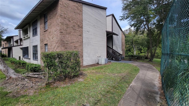 view of side of property featuring cooling unit and a yard