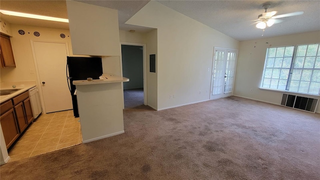 kitchen with vaulted ceiling, light colored carpet, ceiling fan, and a textured ceiling