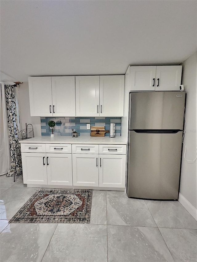 kitchen featuring backsplash, stainless steel fridge, and white cabinets