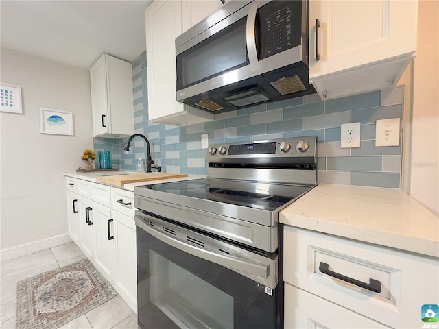 kitchen with stainless steel appliances, light stone countertops, white cabinets, and backsplash