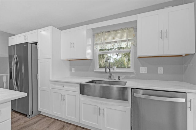 kitchen featuring white cabinetry, sink, stainless steel appliances, and light wood-type flooring