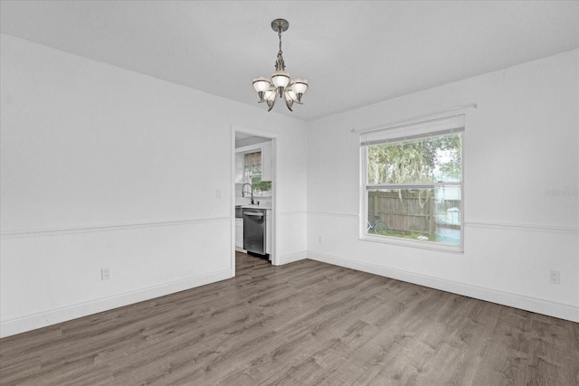 empty room featuring wood-type flooring and a notable chandelier