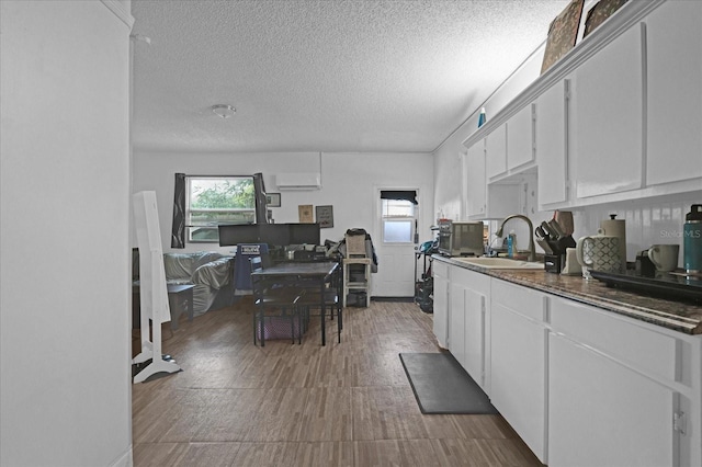 kitchen featuring a textured ceiling, sink, an AC wall unit, white cabinets, and dark hardwood / wood-style floors