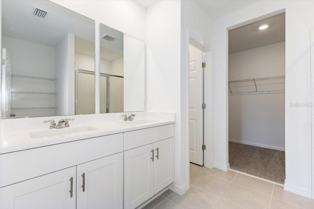 bathroom with tile patterned flooring, vanity, and walk in shower