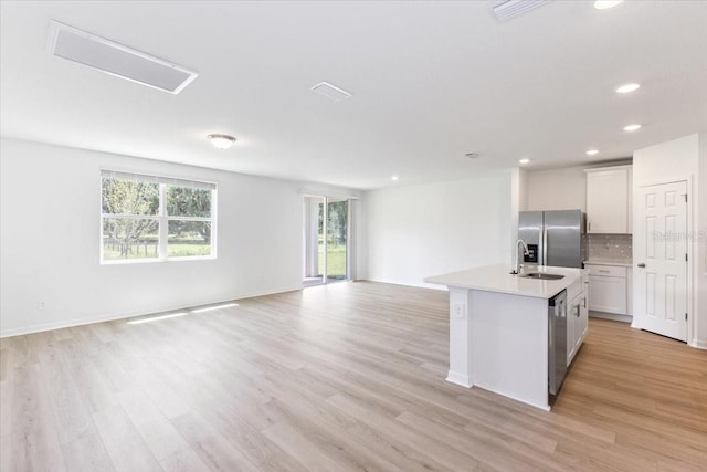 kitchen featuring tasteful backsplash, a center island with sink, light hardwood / wood-style floors, and appliances with stainless steel finishes