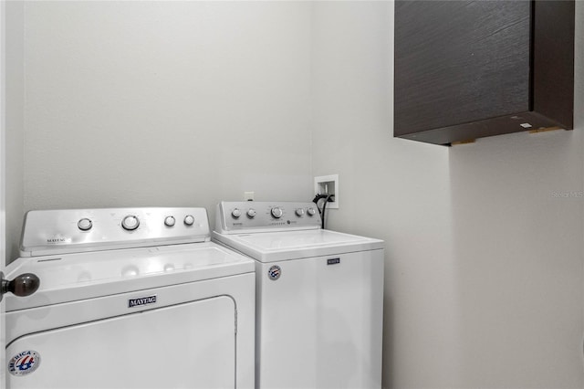 clothes washing area with washing machine and clothes dryer and cabinets