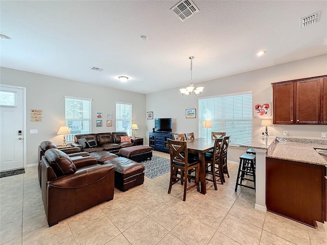 living room featuring plenty of natural light, light tile patterned flooring, and an inviting chandelier