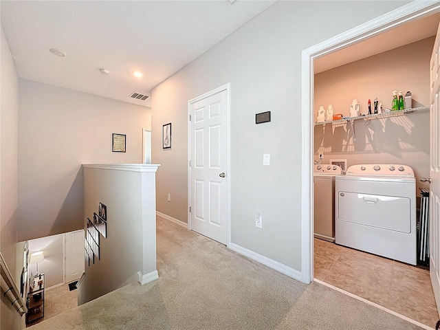 clothes washing area with washing machine and clothes dryer and light colored carpet