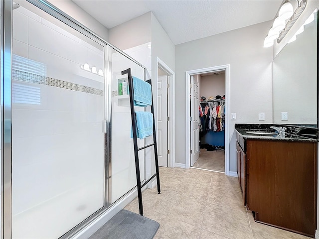 bathroom with a textured ceiling, vanity, walk in shower, and tile patterned floors