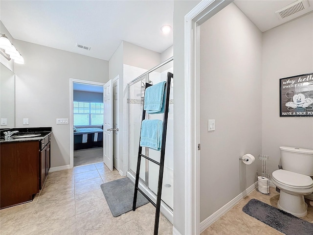 bathroom featuring tile patterned flooring, vanity, a shower with shower door, and toilet