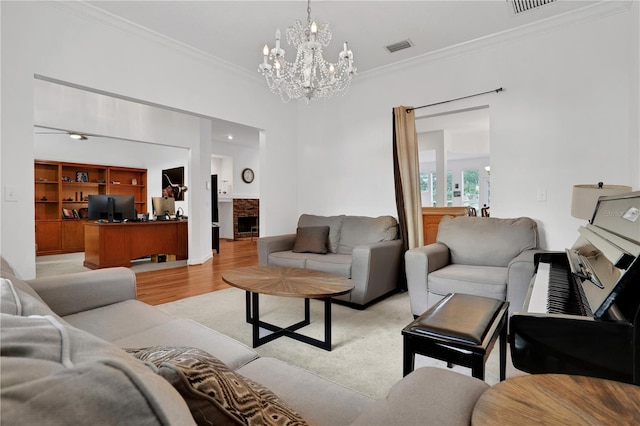 living room featuring light wood-type flooring, crown molding, and a chandelier