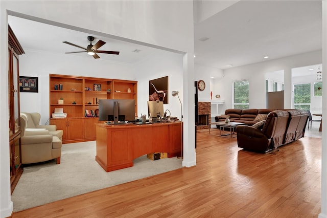 office area with a fireplace, ceiling fan, light hardwood / wood-style flooring, and ornamental molding