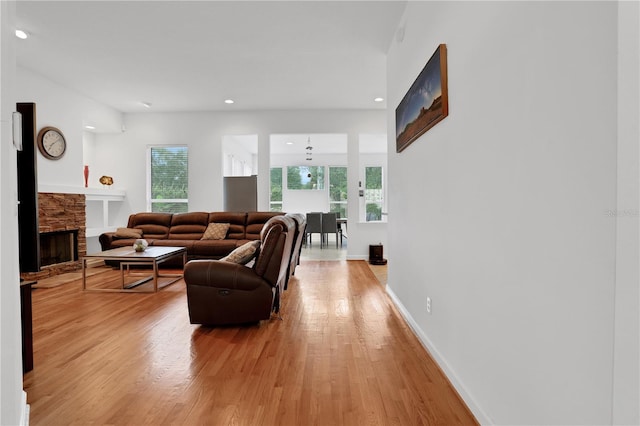 living room with a stone fireplace and light wood-type flooring