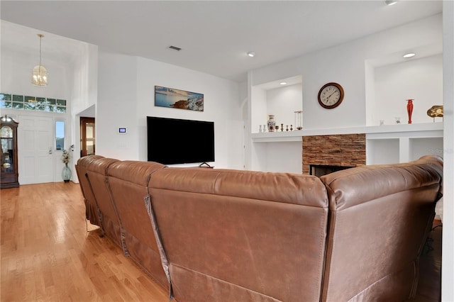 living room featuring a fireplace, light hardwood / wood-style floors, and a notable chandelier