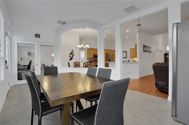 dining space with french doors, light hardwood / wood-style floors, and a notable chandelier