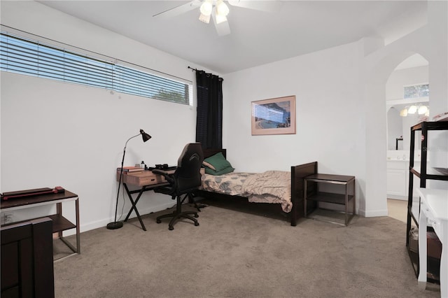 bedroom with ensuite bath, ceiling fan, and light carpet